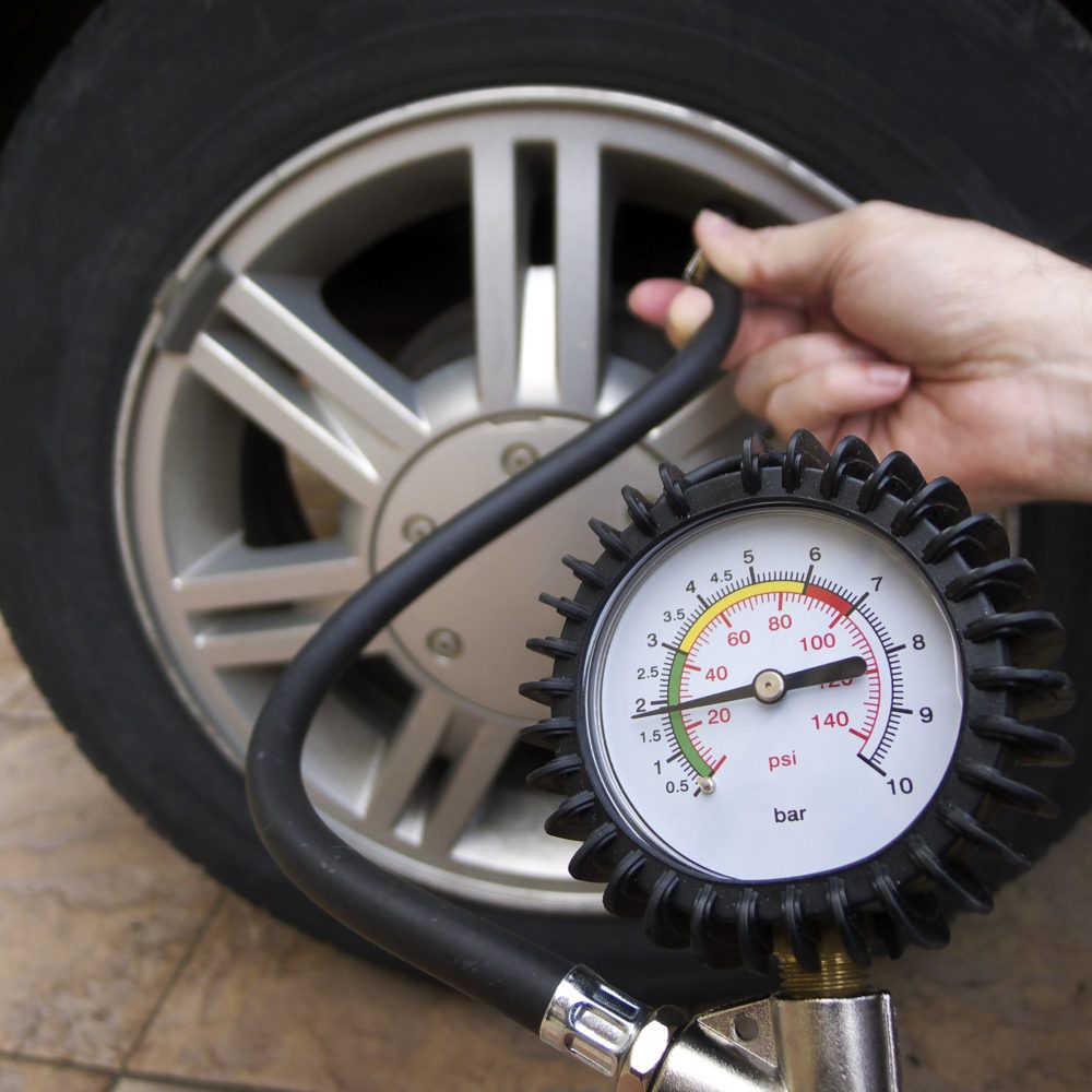 Close-up of manometer and man hands checking tyre pressure with gauge