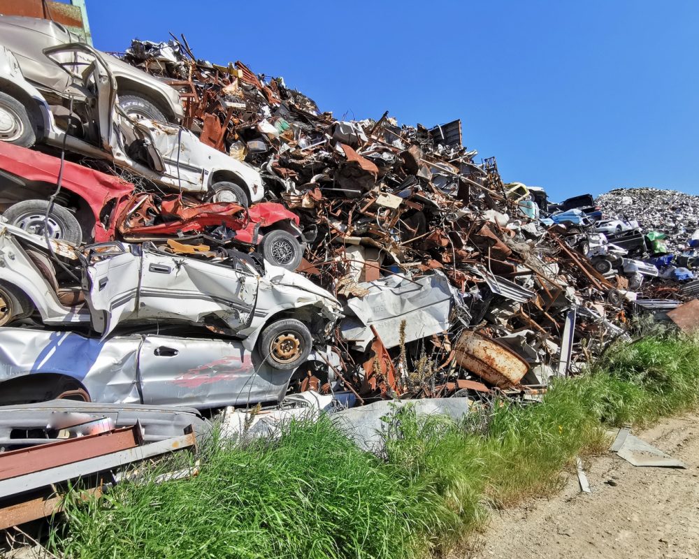 Pile of various scrap cars and other metals on a junk yard field ready recycling industry. Environmental pollution